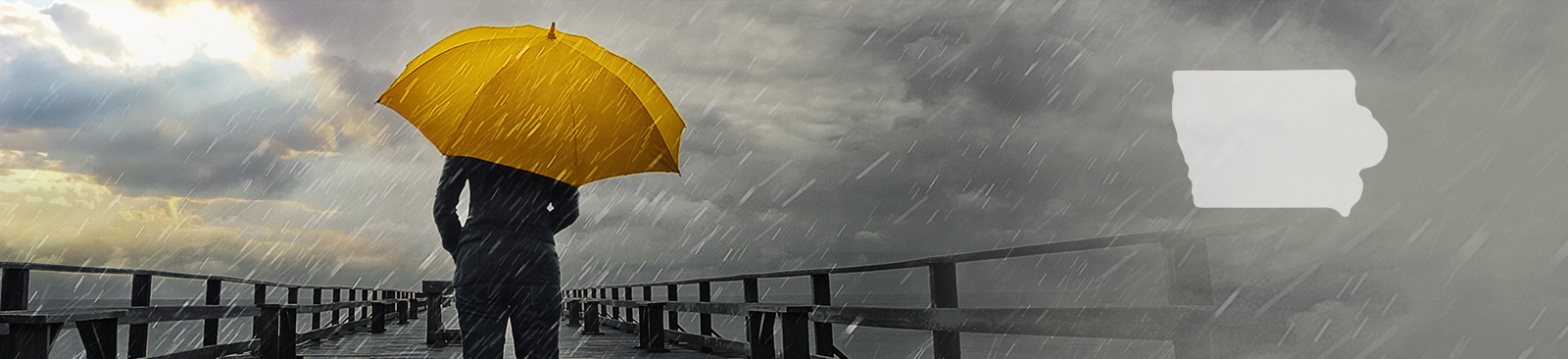 A person stands with their back to the camera, carrying a bright yellow umbrella in the middle of a storm. They stand on a pier, looking out at the stormy sky, which simultaneously looks threatening and hopeful as some of the clouds part to reveal a glimpse of sunshine.